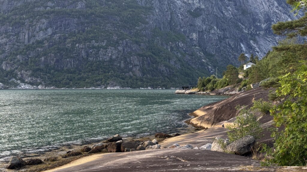 Skalista plaża i turkusowa woda fiordu Eidfjord wieczorem