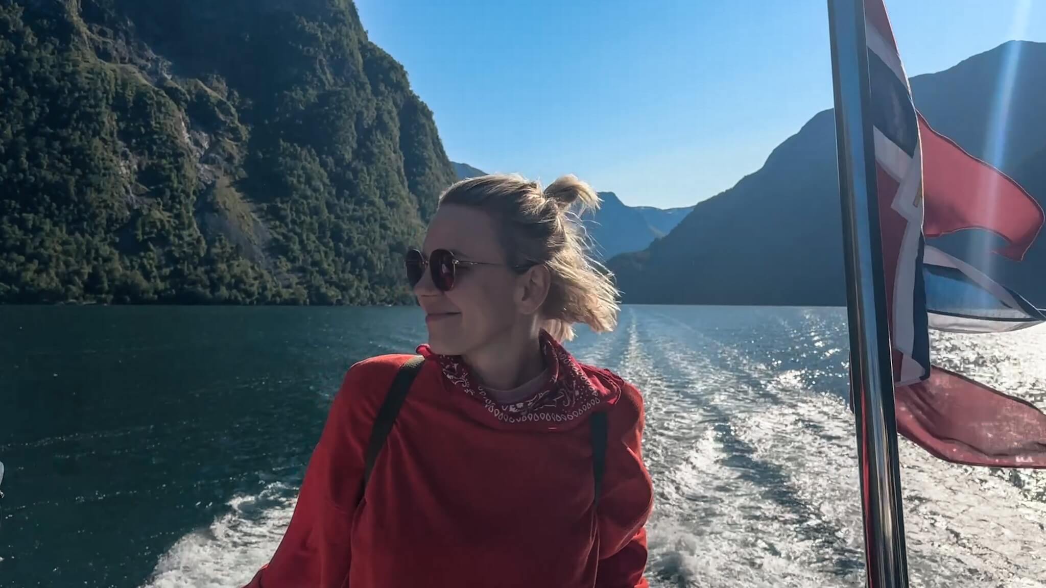 Kobieta na pokładzie statku podczas rejsu przez Nærøyfjord, obok norweska flaga