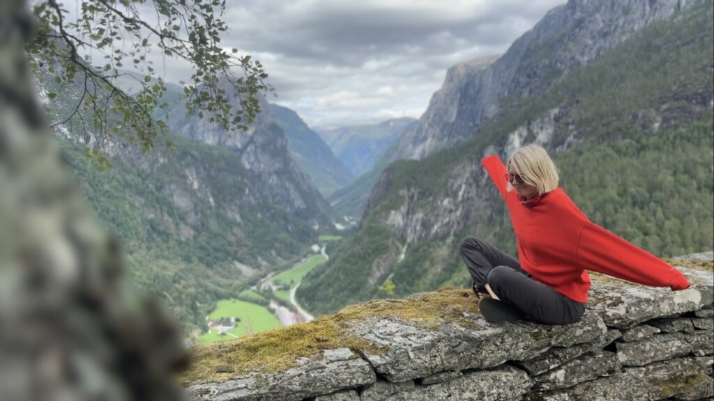Kobieta siedząca na skale z widokiem na dolinę Nærøydalen ze Stalheim